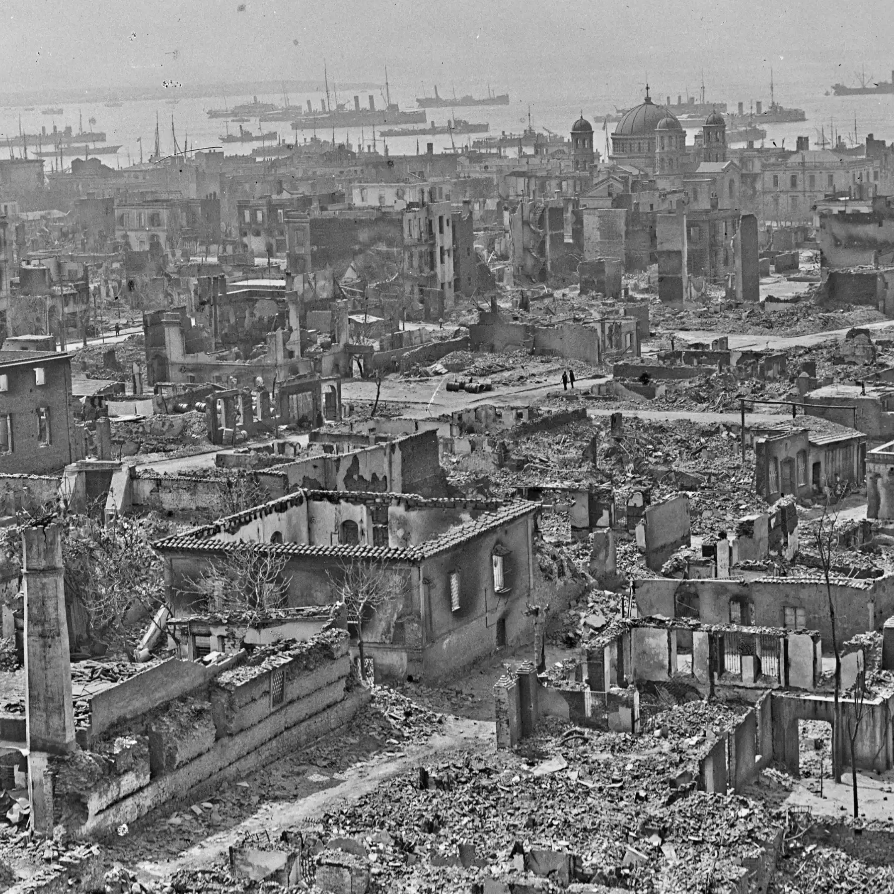 A black and white aerial photo of a city in ruins, with rows of destroyed and damaged buildings extending across the landscape.