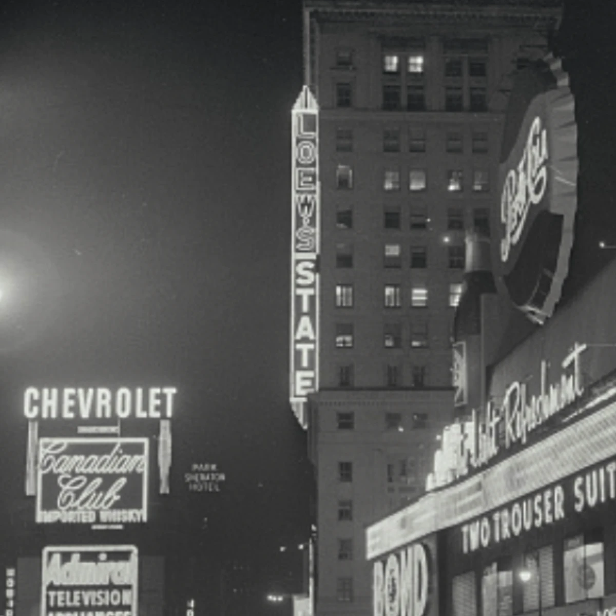 A black and white photo of a nighttime urban city shows vintage neon signs on building tops, including "LOEW'S STATE," "CHEVROLET," and “Pepsi-Cola,".
